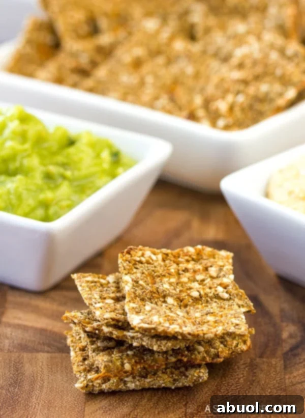 Stack of low carb crackers with different dips in white square dishes in the background.