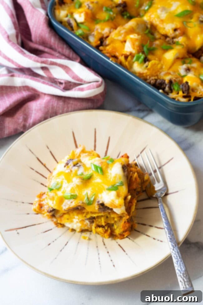 Slice of lasagna on a plate with a fork, ready to be enjoyed.