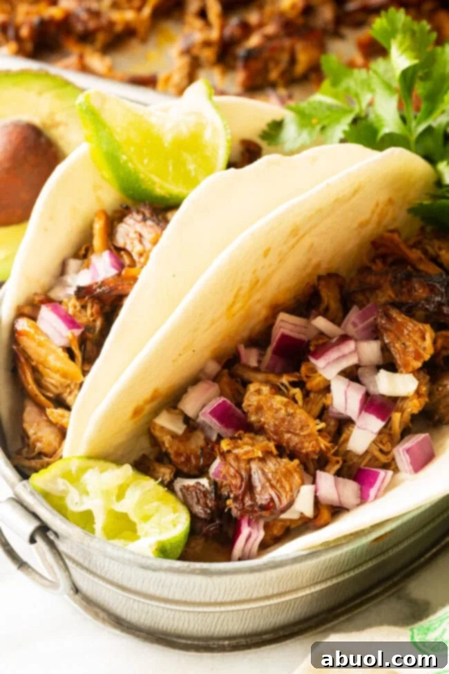 Crispy Instant Pot Carnitas 2 Crispy Instant Pot Carnitas tacos garnished with fresh onions and cilantro on a wooden board