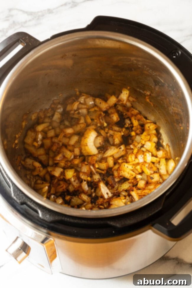 Crispy Instant Pot Carnitas 6 Chopped onion being added to the Instant Pot for Instant Pot Carnitas