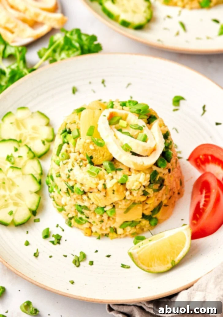 Thai fried rice recipe in a mound on a plate next to tomatoes, cucumbers and limes. 