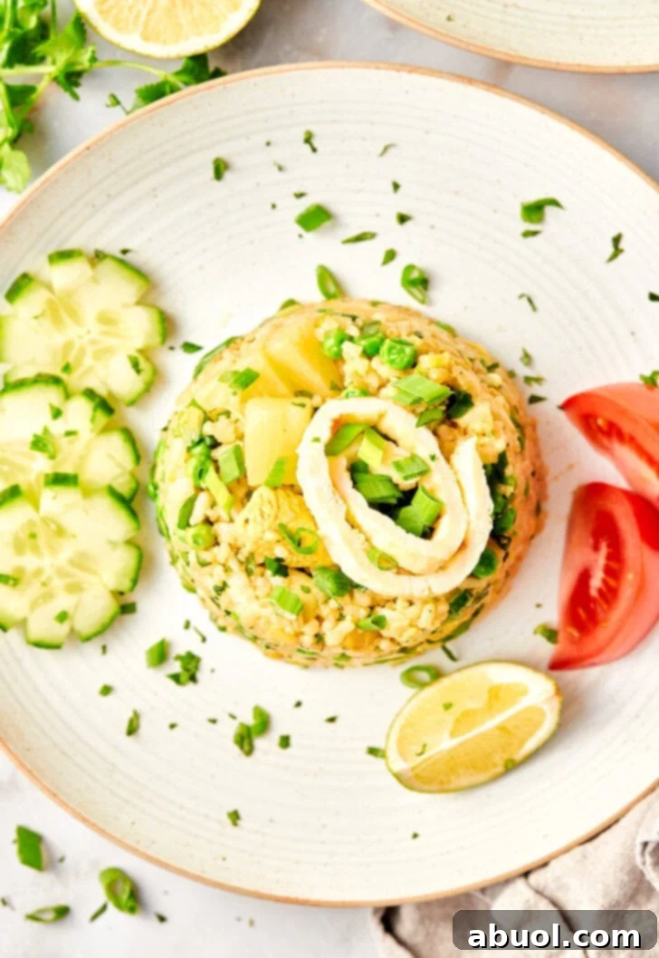Perfect Thai Fried Rice on a plate next to cucumbers, tomatoes, limes and chop sticks.