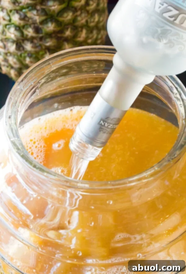 Goombay Punch ingredients pouring into large batch jug