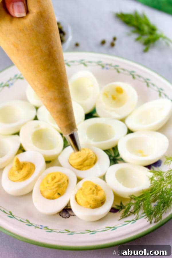 Piping creamy filling into egg whites for deviled eggs.