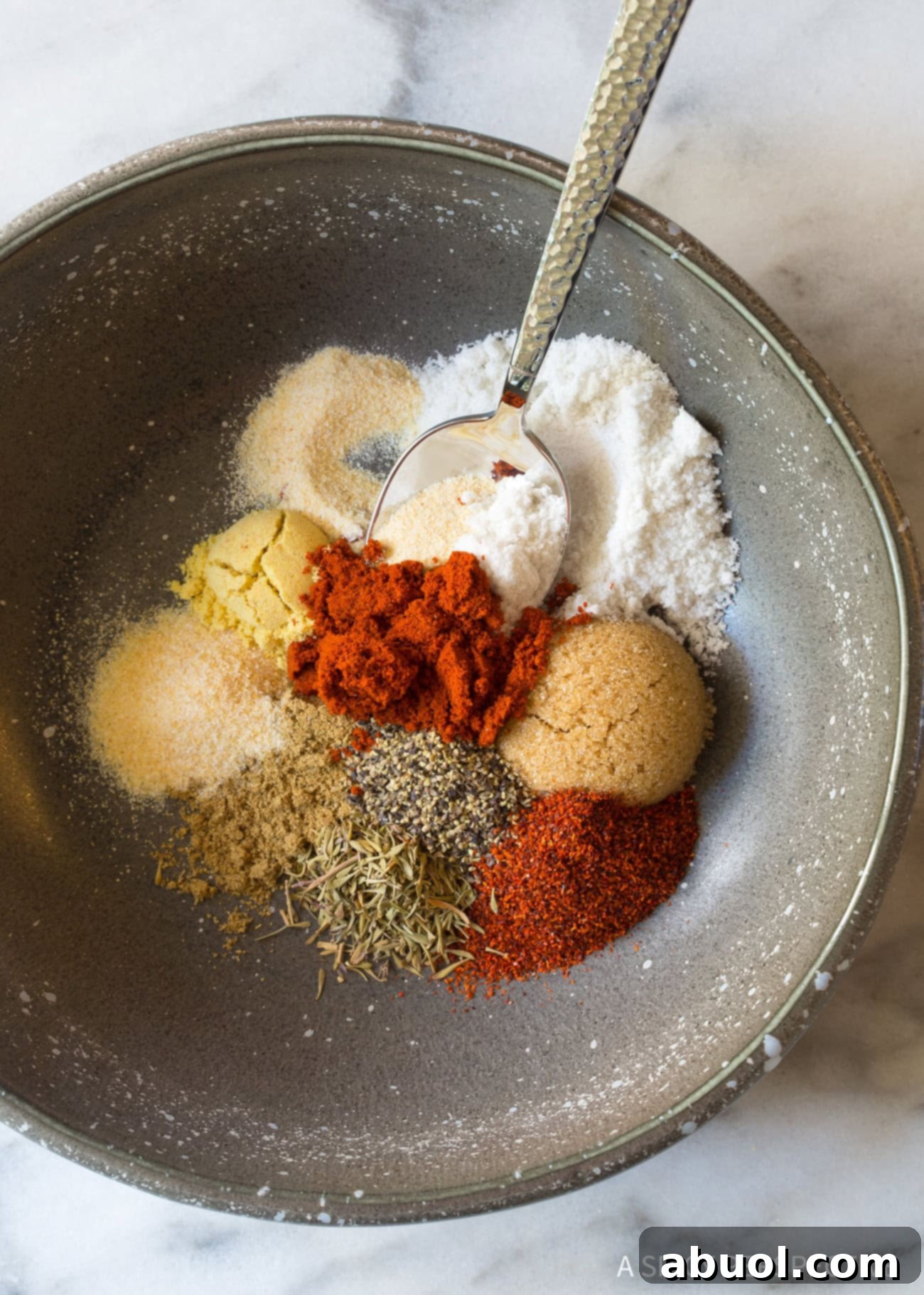 A small bowl filled with a rich blend of herbs and spices, essential for creating the perfect steak seasoning.