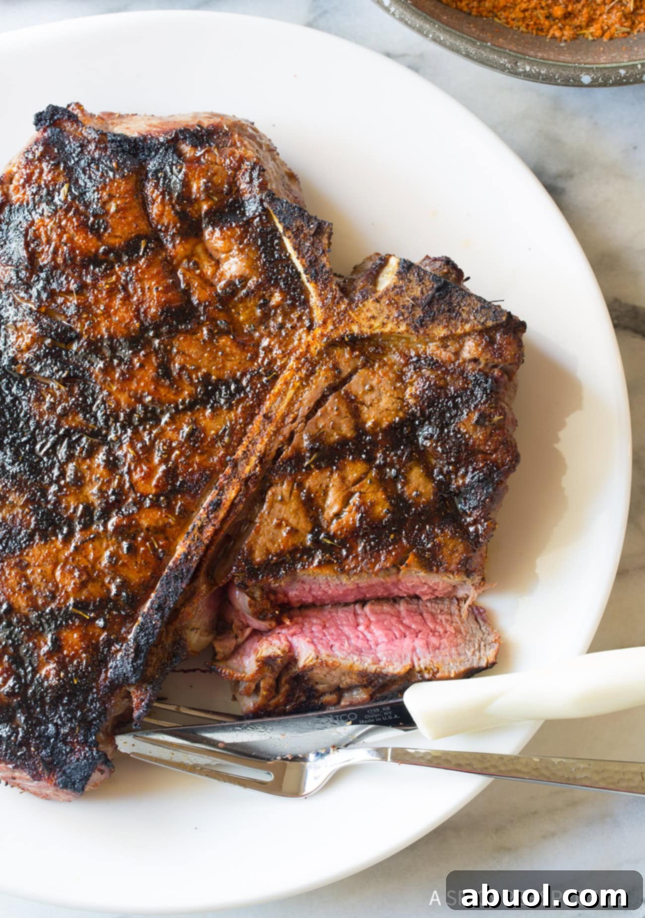 A perfectly cooked medium-rare steak on a plate with a slice cut out, showcasing its juicy interior.