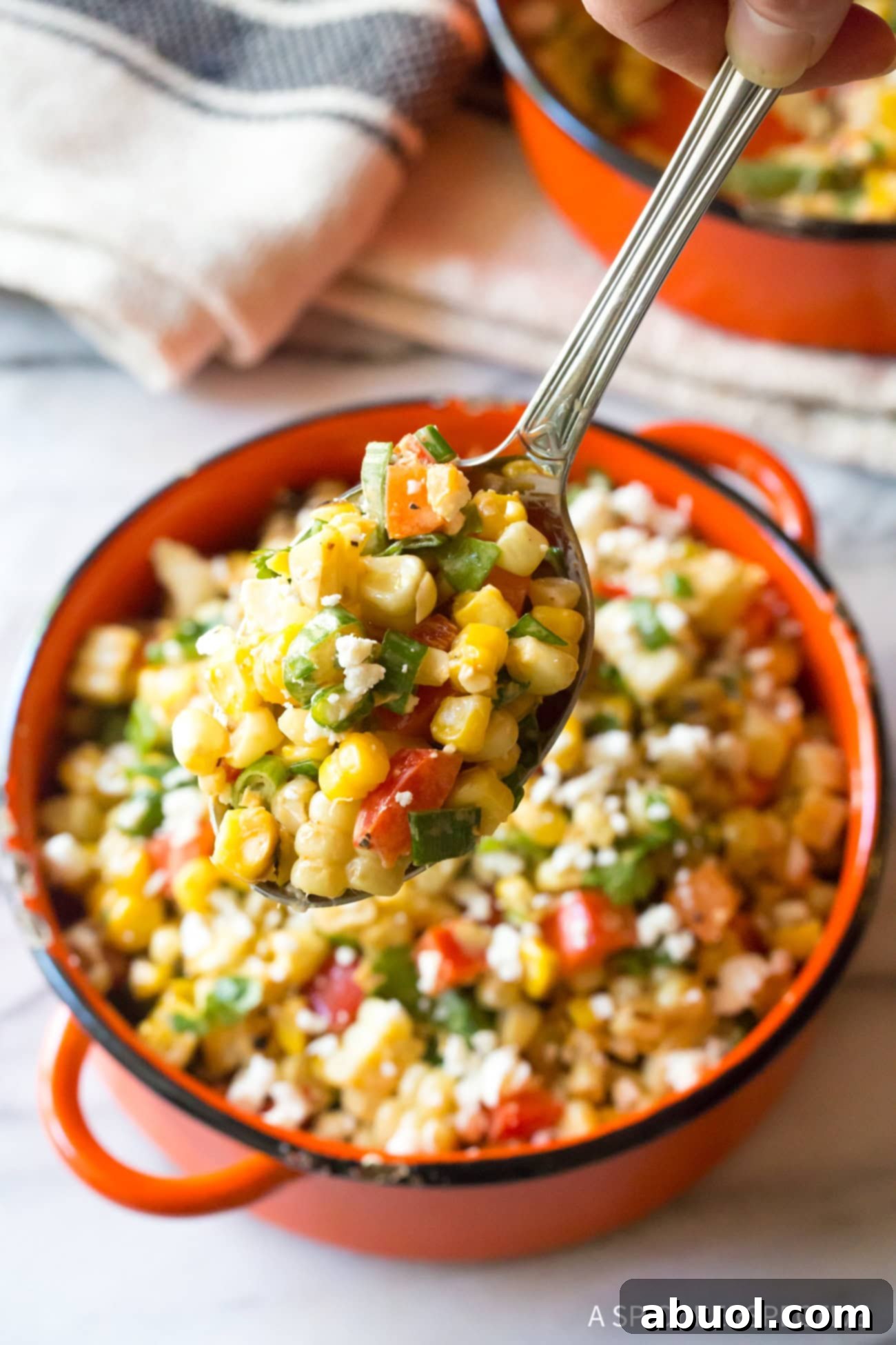 Closeup of spoon lifting a scoop of Mexican Street Corn Salad from the bowl. 