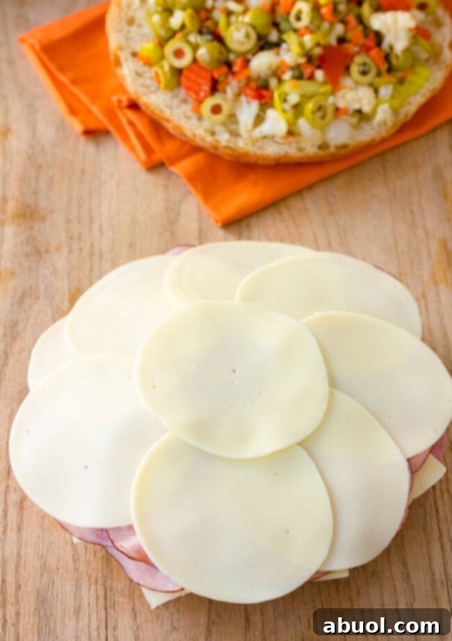 The assembled Muffuletta sandwich, beautifully pressed, is cut into quarters, revealing its impressive layers and inviting presentation.