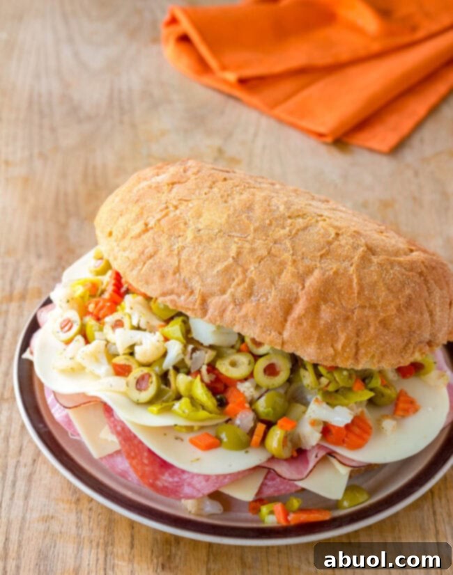 A magnificent New Orleans Muffuletta sandwich, brimming with layers of meat, cheese, and olive salad, sits proudly on a plate.