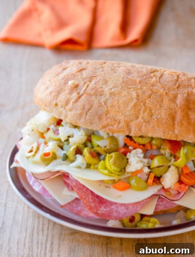 An amazing New Orleans Muffuletta Sandwich, perfectly assembled and sliced, served on a plate ready to be enjoyed.