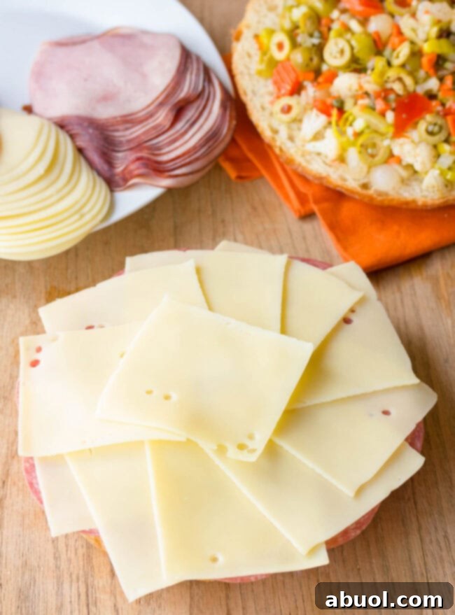 A generous, chunky olive salad is spread over the layers of meat and cheese, its vibrant colors and textures promising an explosion of flavor.