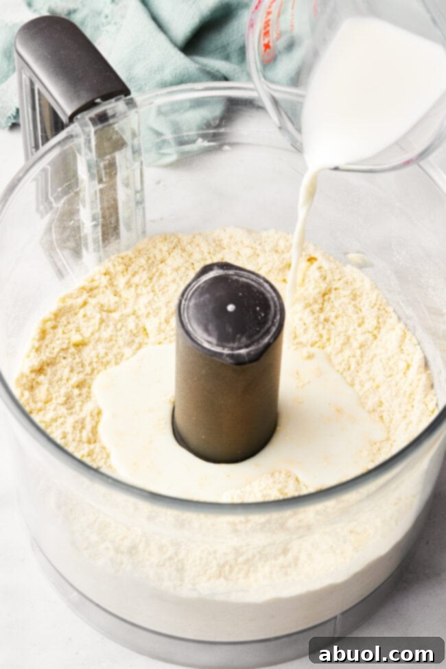 Dry ingredients for shortcakes – flour, cornmeal, baking powder, salt, and sugar – being added to a food processor bowl.