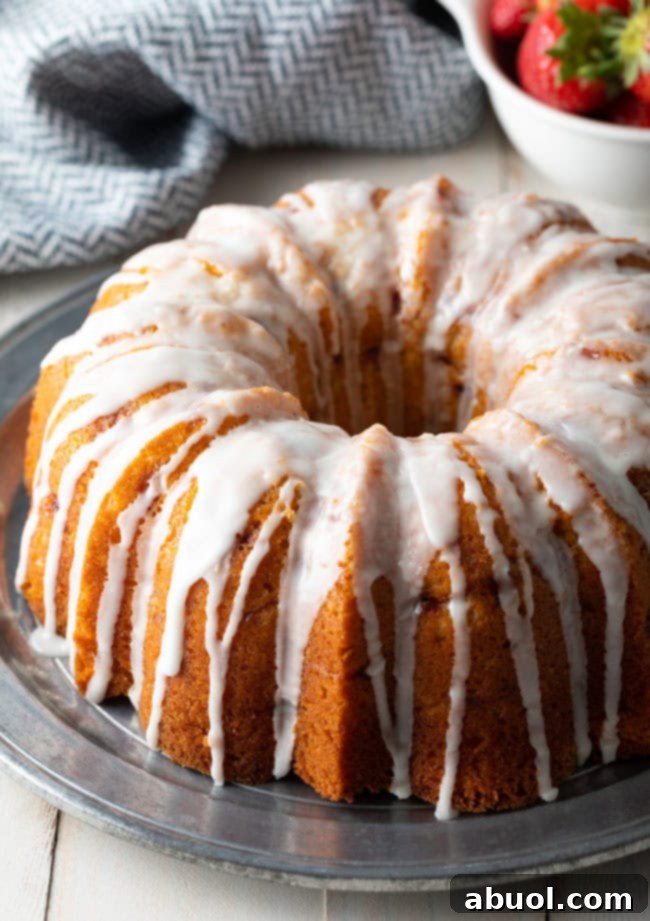 Fully prepared strawberry bundt cake with lemon glaze on a silver serving plate.