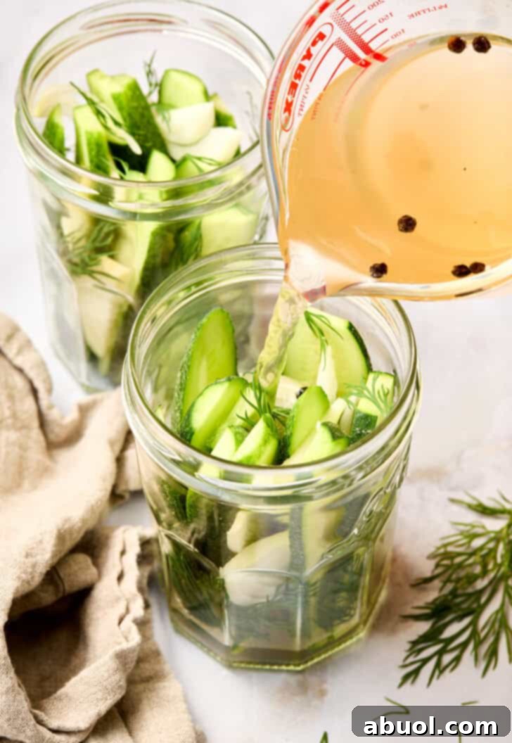 Process of pouring warm pickling brine into a jar filled with cucumbers and spices