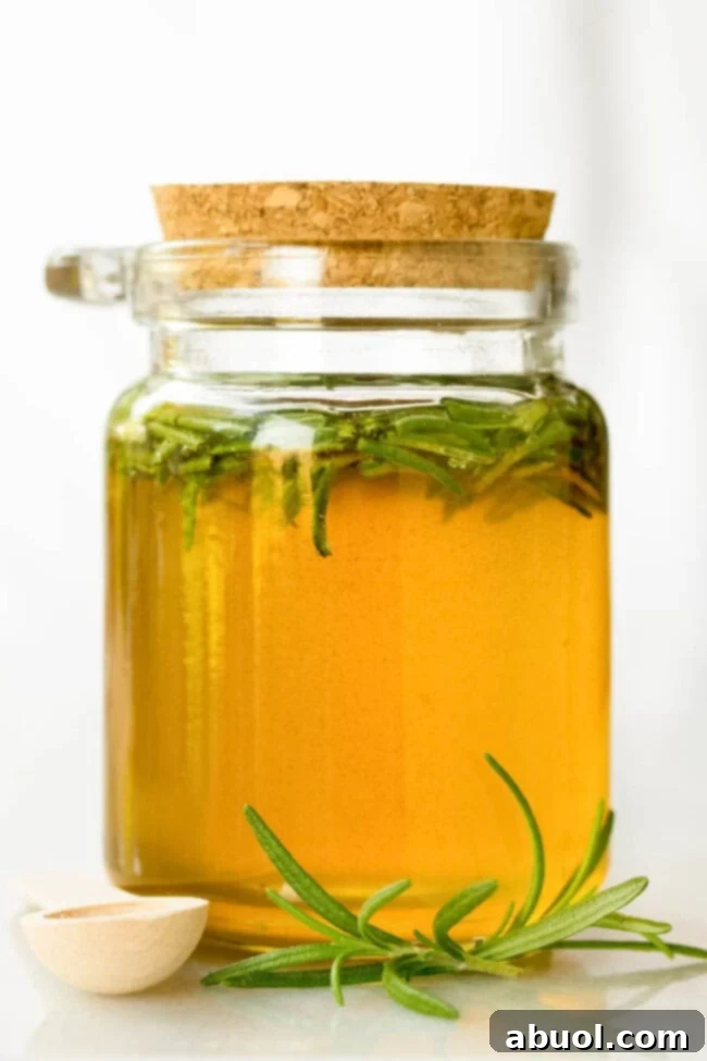 A meticulously sealed small glass jar contains golden spiced honey, with a sprig of fresh rosemary elegantly suspended within, ready to be presented as a thoughtful gift.