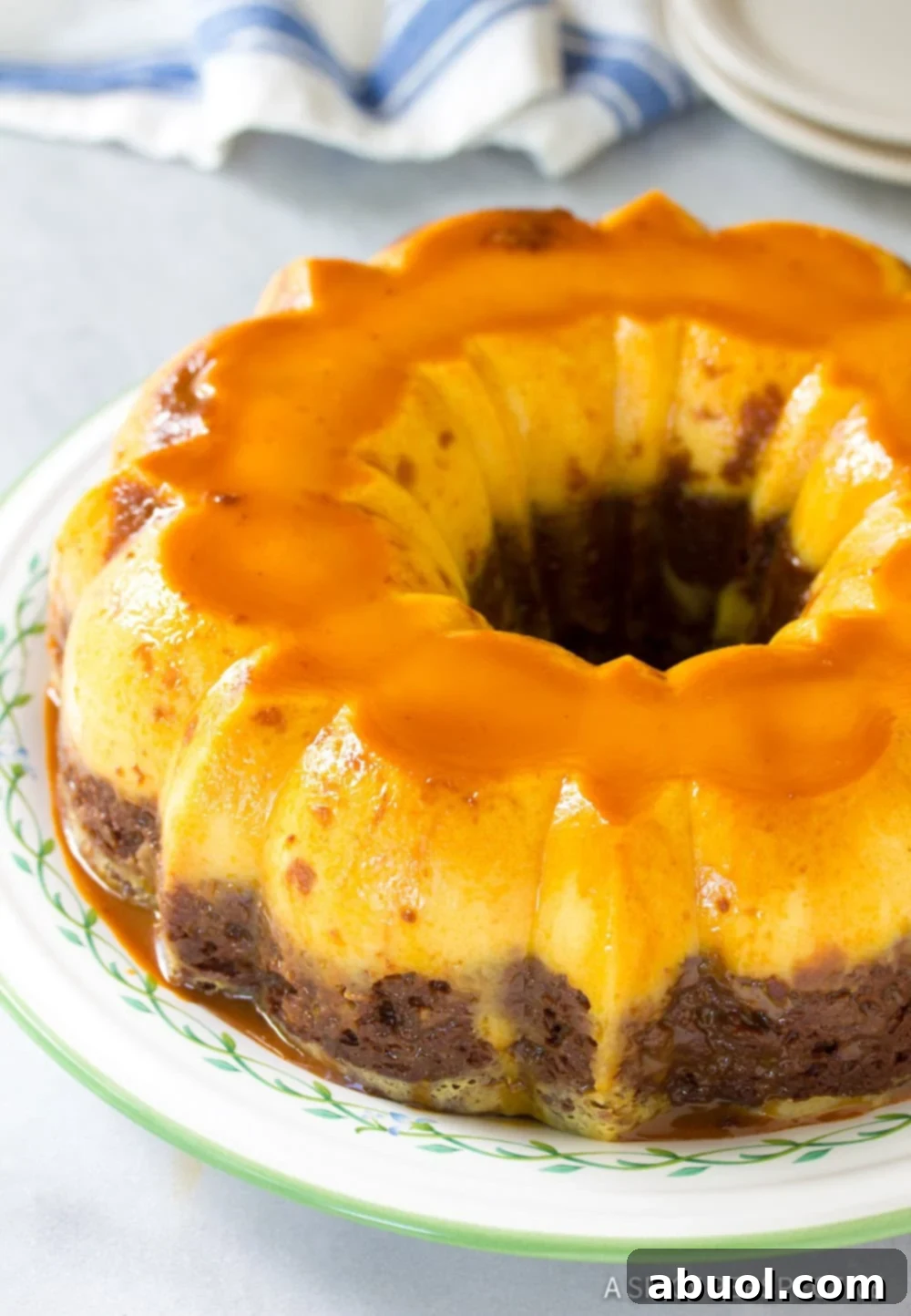 A whole Chocoflan cake beautifully inverted onto a round serving platter, showing off its shiny caramel glaze, ready to be sliced and served.