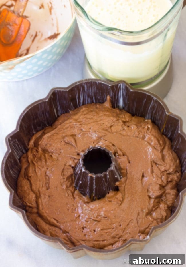 Close-up of the chocolate cake batter being spooned into the caramel-lined bundt pan for the Chocoflan.