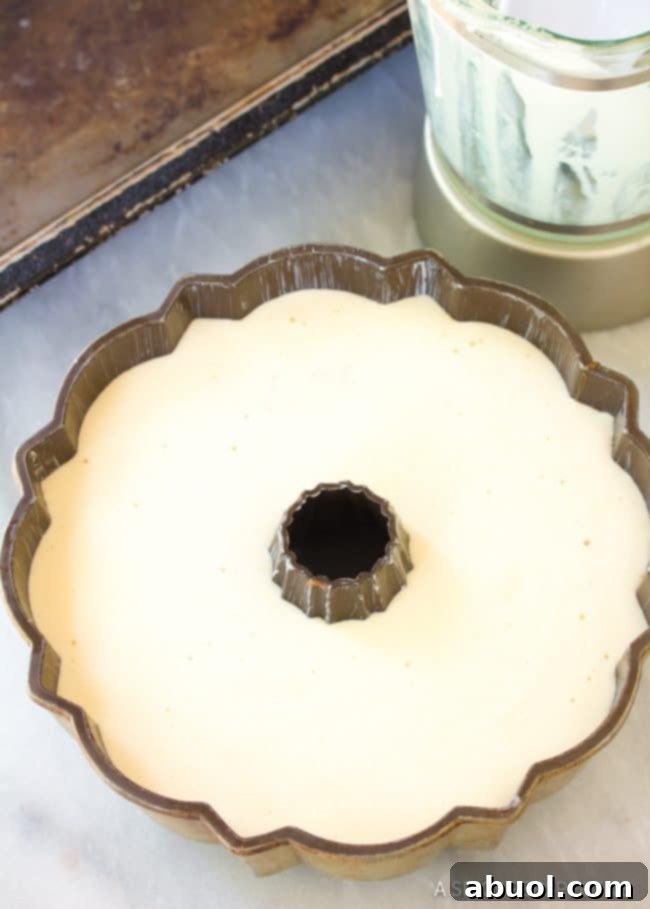 The Chocoflan bundt pan covered with foil, placed in a water bath inside a roasting pan, ready for the oven.