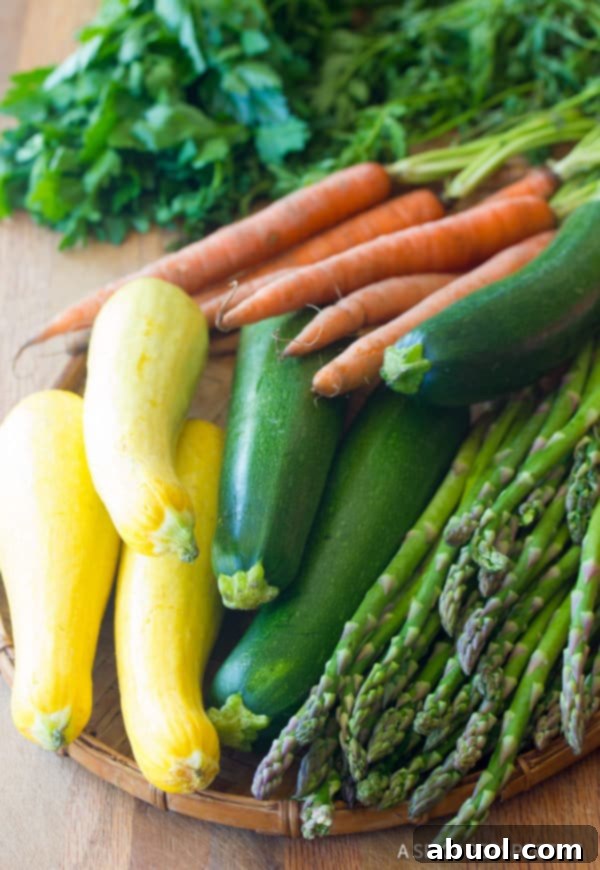 A vibrant selection of vegetables, including squash, zucchini, asparagus, and carrots, prepped for roasting.