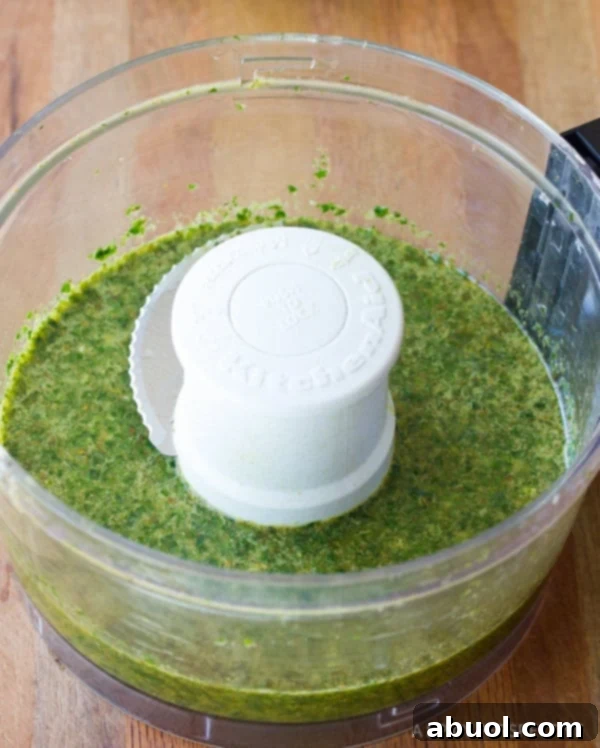 Fresh chimichurri sauce being blended in a food processor, showcasing its vibrant green color.