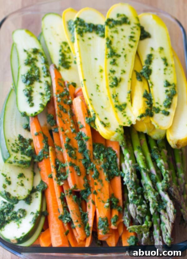 Assorted sliced vegetables generously coated in chimichurri, ready for grilling or roasting.