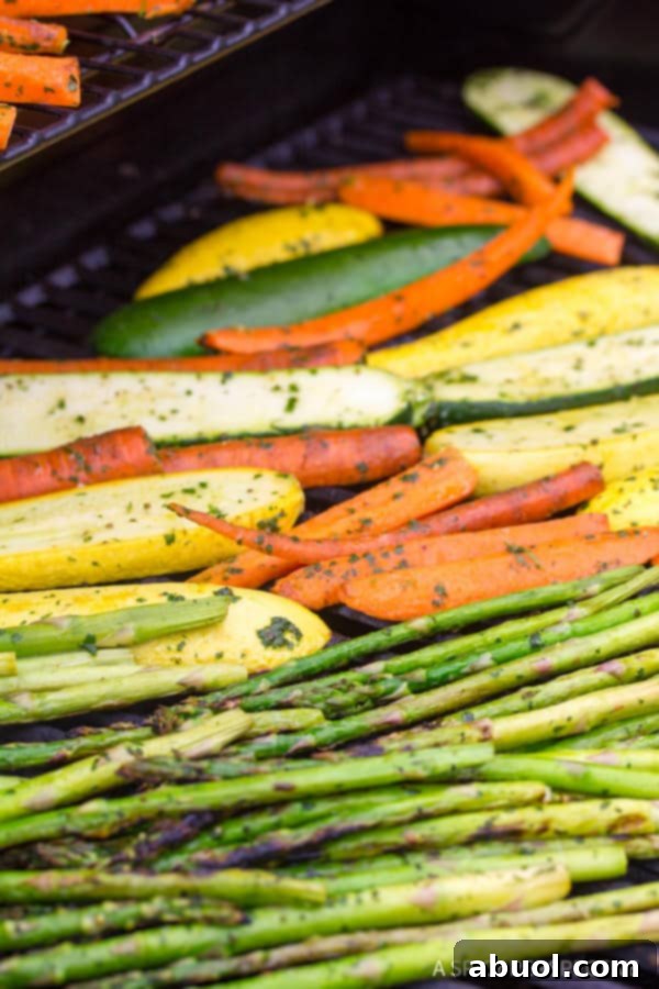 Colorful vegetables, including squash, zucchini, and carrots, perfectly charring on a hot grill.