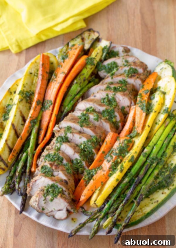 A comprehensive tray displaying a beautifully cooked Grilled Pork Tenderloin with Chimichurri and a medley of Roasted Vegetables.