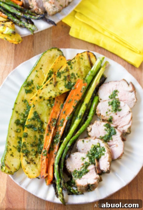 A beautifully presented plate of grilled pork tenderloin, artfully drizzled with fresh chimichurri, highlighting its vibrant flavors.