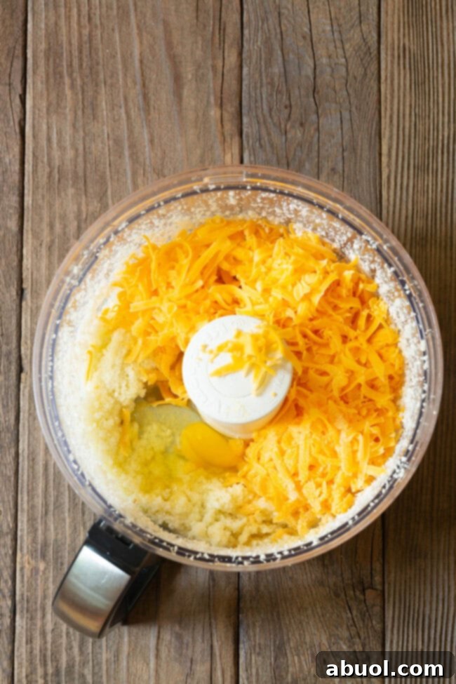 The key ingredients for cauliflower tortillas – cauliflower florets, shredded cheese, eggs, and spices – ready in a food processor for blending.