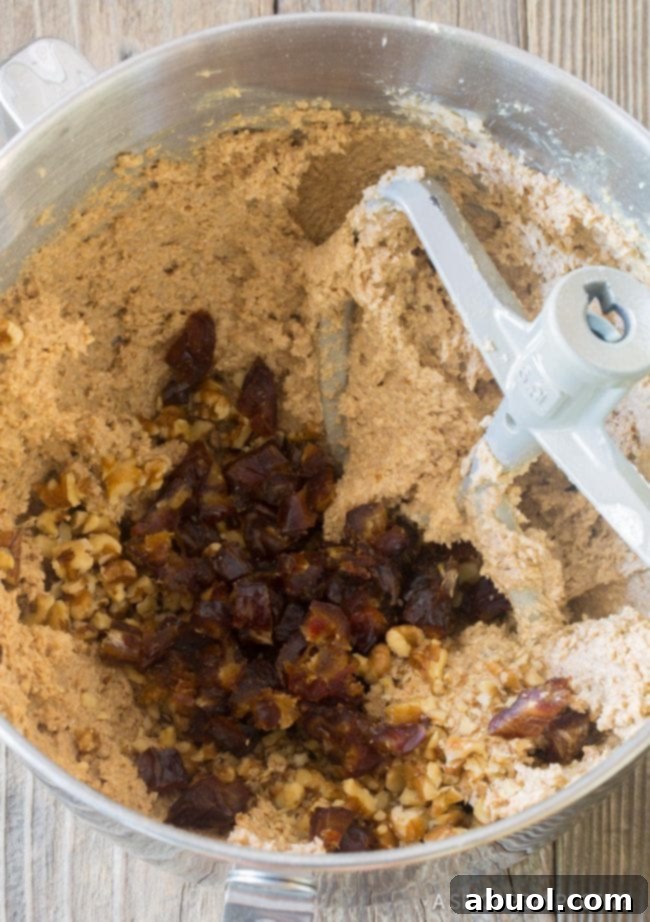 Breakfast oatmeal bar batter being mixed in a food processor, with chopped dates and nuts visible on top, showcasing the texture.