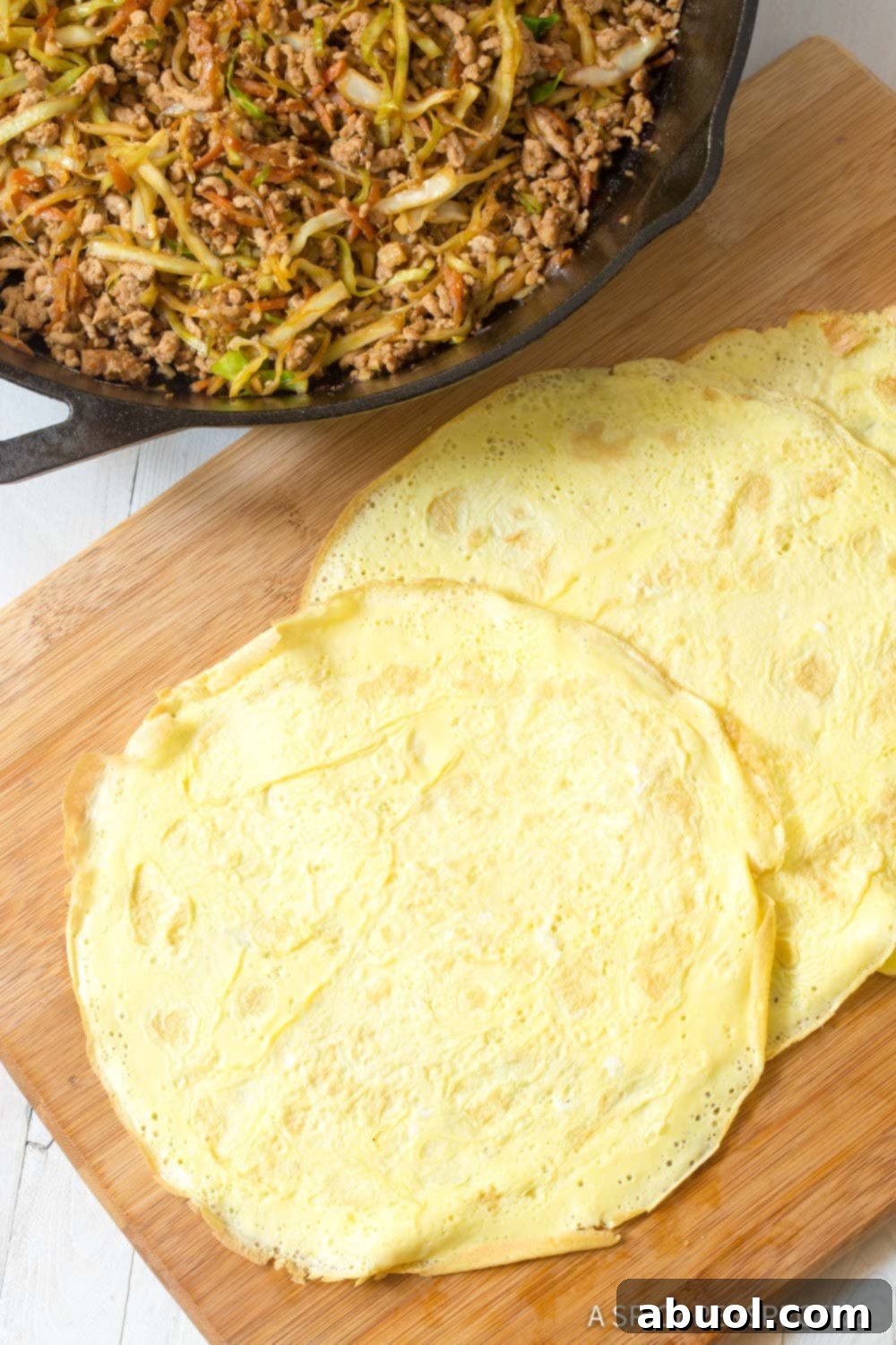 How to Make Keto Egg Roll Wrappers - Flat egg wraps laid on a cutting board, ready for filling