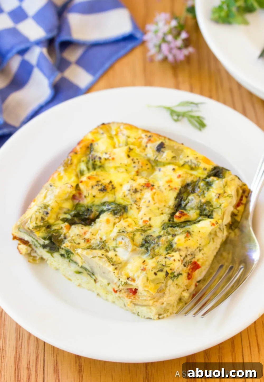 A close up photo of a slice of Greek omelette casserole on a white plate, highlighting its rich texture and color.