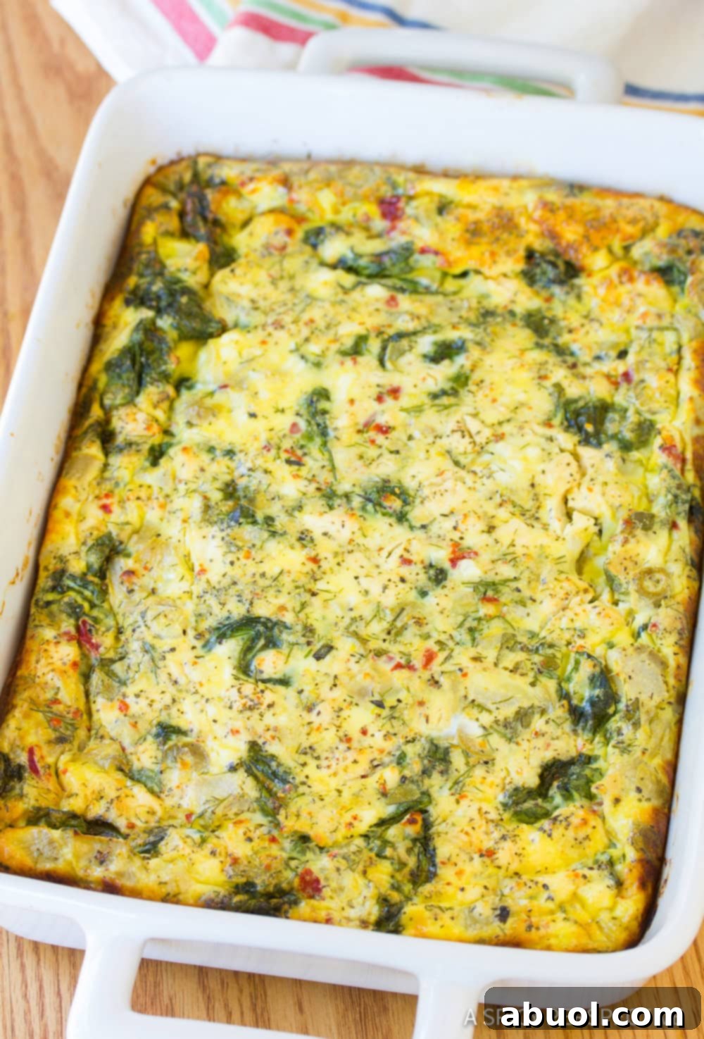 A close up view of the finished Greek omelette casserole in a white baking dish, showing its delicious texture.