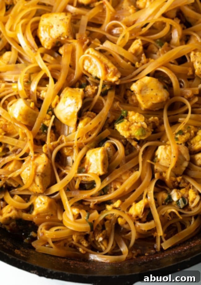 A close-up, top-down view of authentic Chicken Pad Thai noodles elegantly presented in a cast iron skillet, highlighting the rich colors and textures of the dish, ready to be enjoyed.