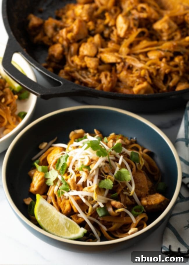 A beautifully presented bowl of homemade Pad Thai noodles, garnished with fresh mung bean sprouts, bright lime wedges, and fragrant cilantro, showcasing the dish's irresistible appeal.