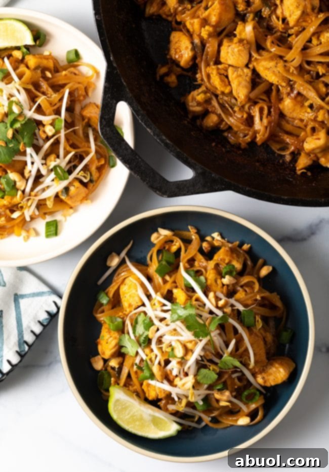 Overhead shot of freshly prepared Pad Thai noodles in a bowl, garnished with vibrant mung bean sprouts, wedges of lime, and fresh cilantro, ready to be enjoyed.