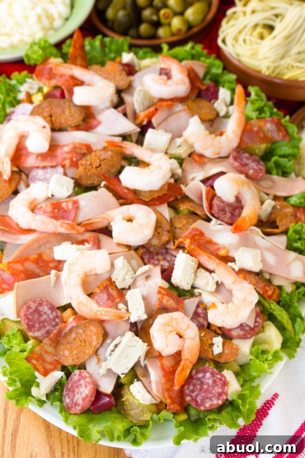 Cured meats and shrimp on a bed of lettuce on a serving tray. 