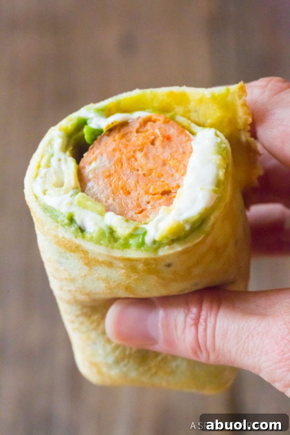 Hand holding a delicious breakfast egg wrap recipe.