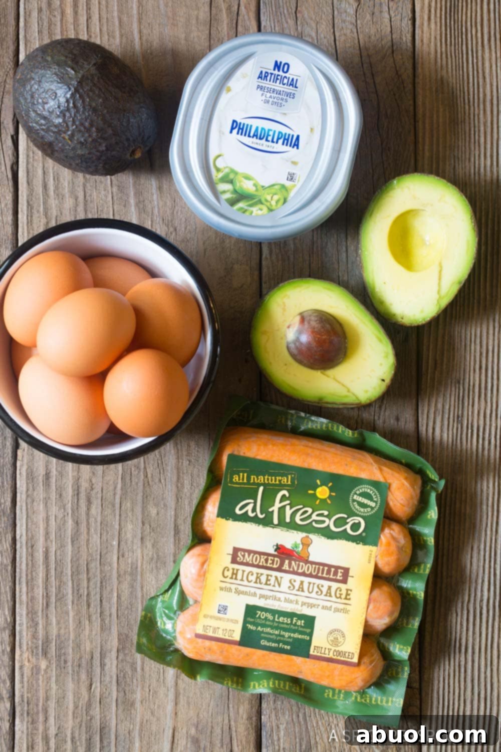 Ingredients needed for homemade breakfast wraps including eggs, chicken sausages, avocado, and cream cheese.