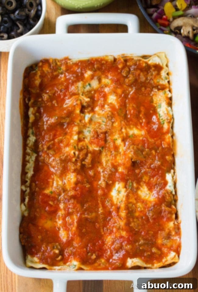 Epic Pizza Lasagna Fusion 5 Top down view of supreme pizza lasagna layered in a white pan, showing the rich filling.
