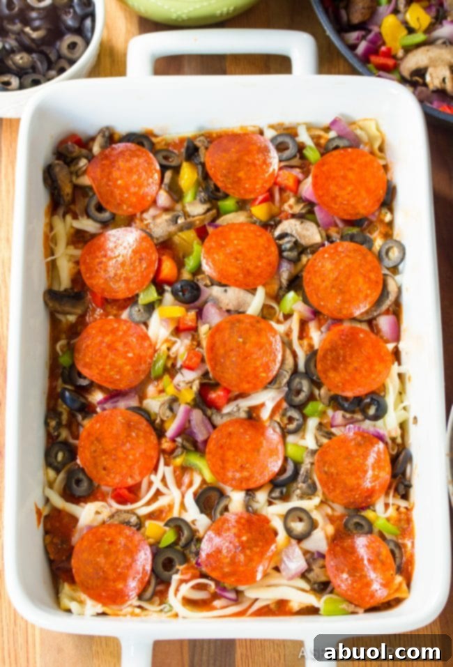 Epic Pizza Lasagna Fusion 6 Top down view of supreme pizza lasagna being assembled in a white pan, highlighting the layers.