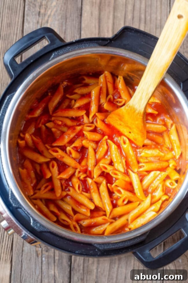 Penne pasta cooking in the tomato sauce in an instant pot.