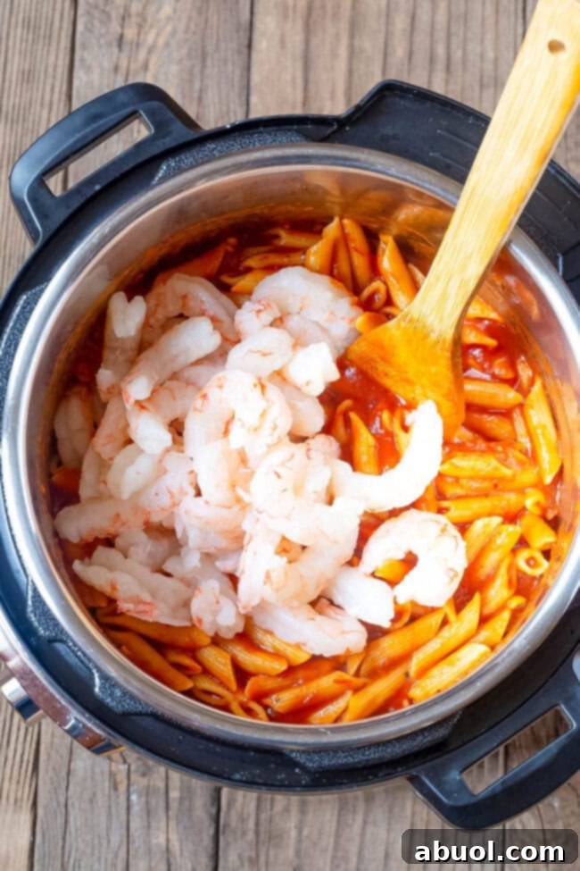 Shrimp being added to the pasta and sauce.