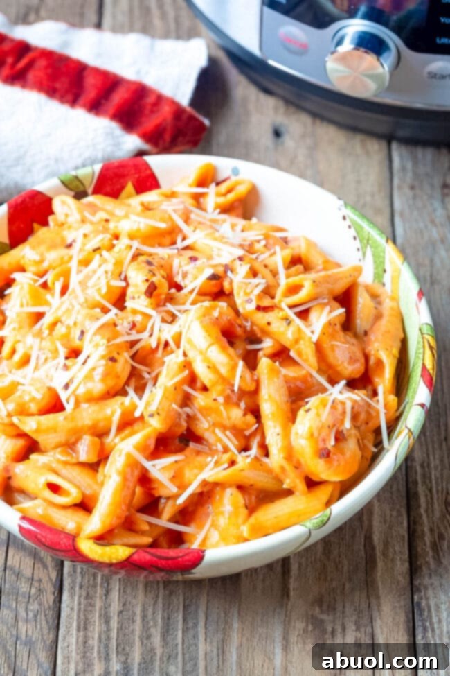 Bowl of shrimp alla vodka and pasta with parmesan on top.