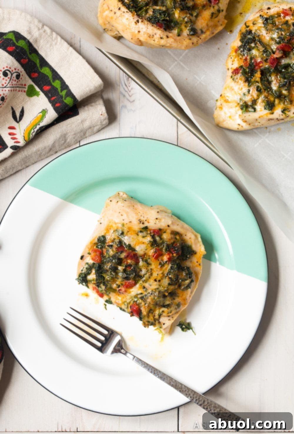 Cheesy Spinach Stuffed Chicken Breast cut in half on a plate with a fork. 