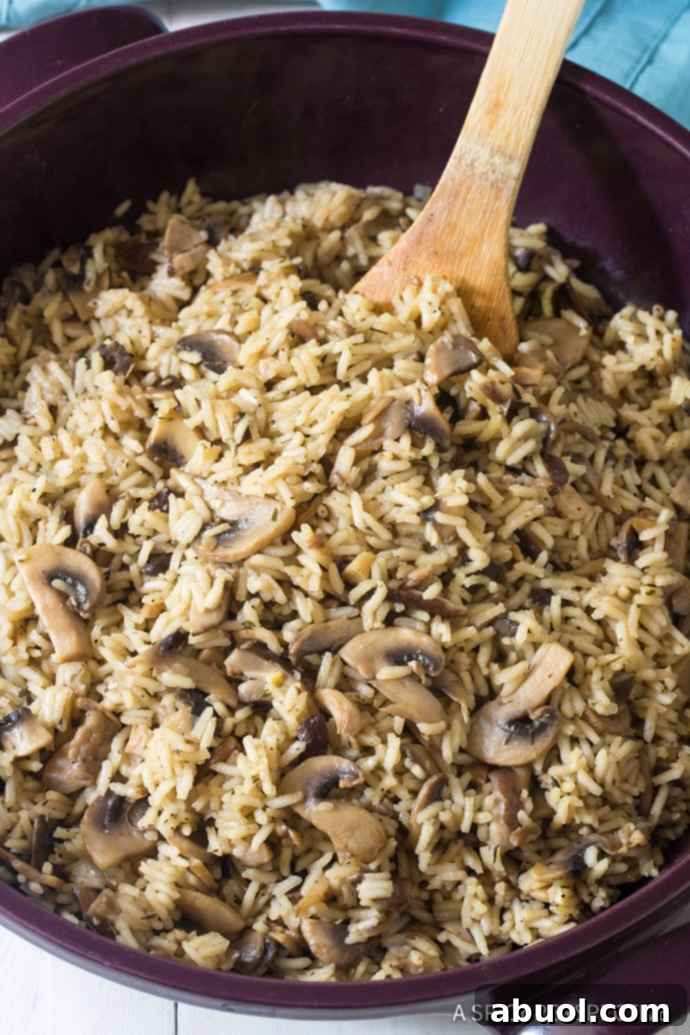 A large pot filled with steaming Mushroom Rice Pilaf, being stirred gently with a wooden spoon, showcasing its rich, earthy texture and vibrant ingredients.