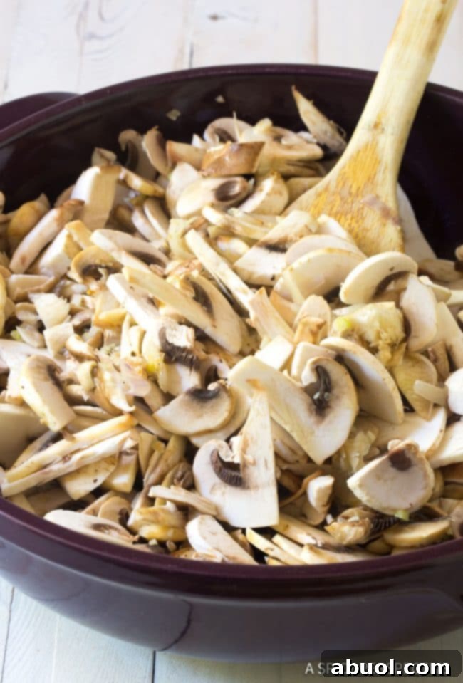 Raw, thinly sliced mushrooms ready for sautéing, resting in a pan with a wooden spoon nearby, promising a flavorful start to the pilaf.