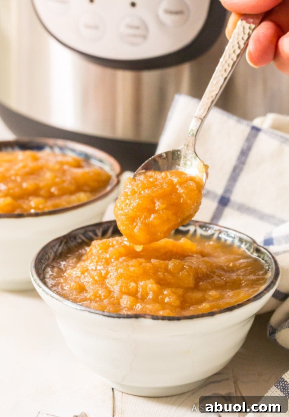 instant pot applesauce in serving bowl, scooped up on spoon