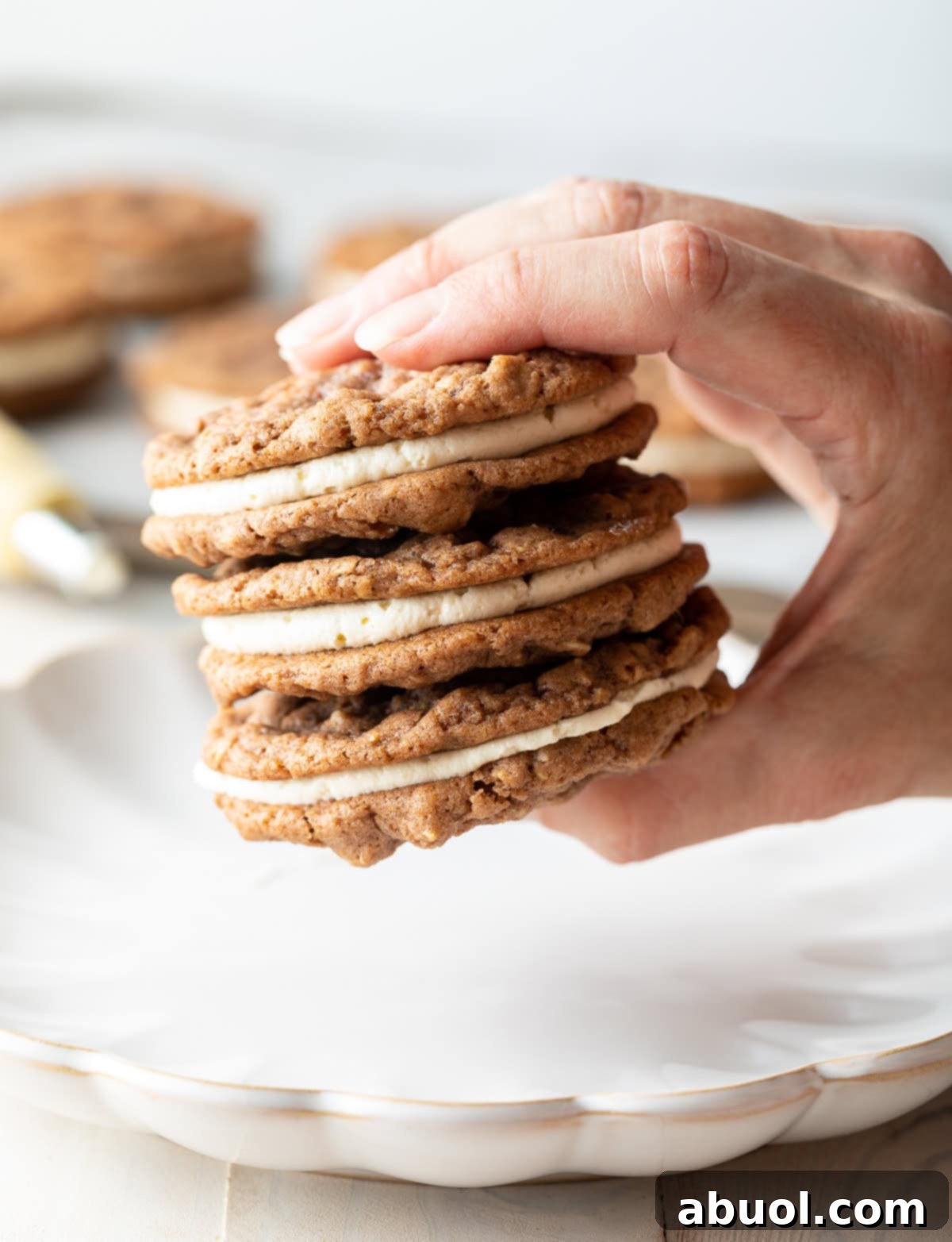 Hand holding three Oatmeal Cream Pies above a serving tray. 