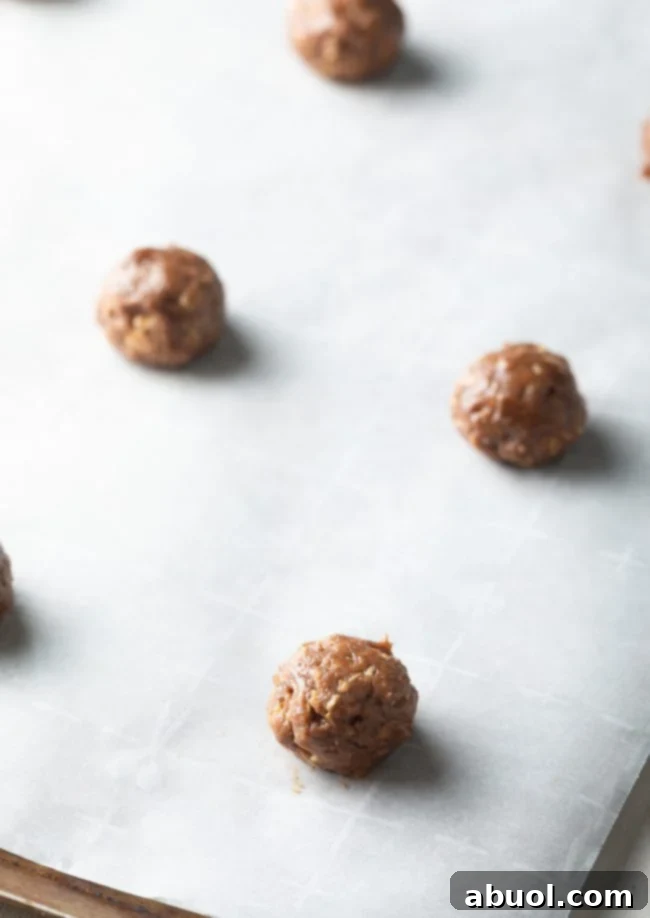 Balls of oatmeal cookie dough on parchment paper. 